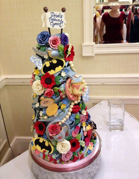 Торт, украшенный логотипами Бэтмена и цветочками, бабочками, бусинками. 